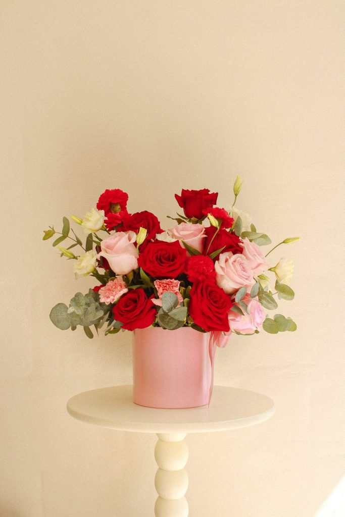 Arreglo Blush de Celiflor con rosas rojas, rosadas y fucsias, claveles y lisianthus en base color rosado, ideal para regalo o decoración romántica.