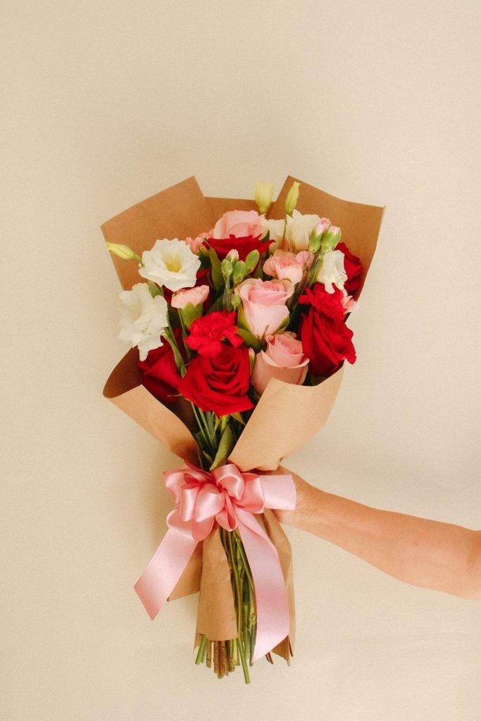Ramo Rosé de Celiflor con rosas rojas, rosadas y fucsias, claveles y lisianthus envueltos en papel encerado artesanal con lazo satinado rosa.