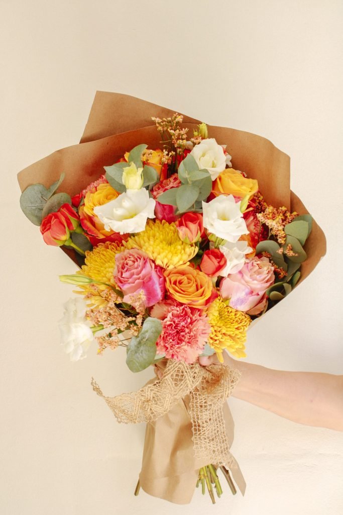 Ramo Sunset de Celiflor, con rosas rosadas, amarillas y naranjas, lisianthus y follajes naturales envuelto en papel encerado artesanal.